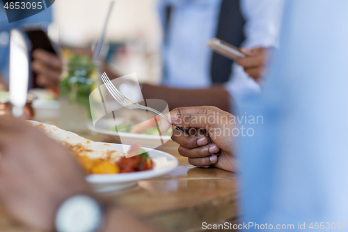 Image of african man eating with friends at restaurant