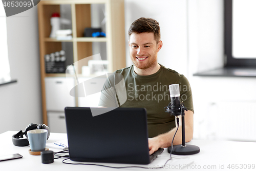 Image of man with laptop and microphone at home office