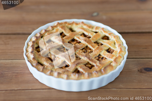 Image of apple pie in baking mold on wooden table