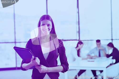 Image of business woman with her staff in background at office