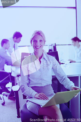 Image of business woman with her staff in background at office