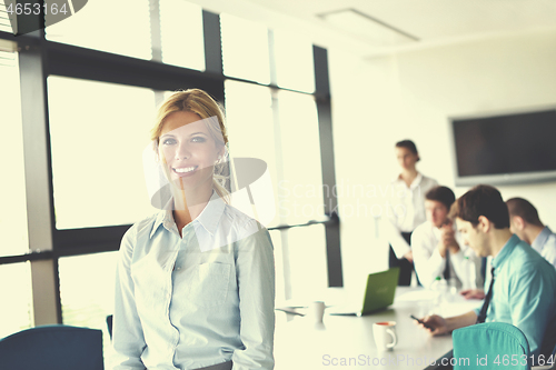 Image of business woman with her staff in background at office