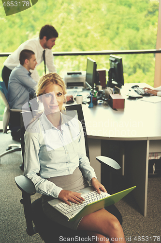 Image of business woman with her staff in background at office