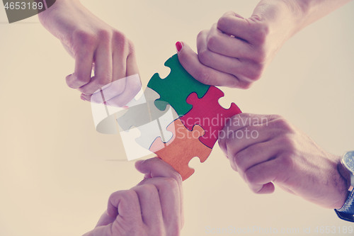 Image of Group of business people assembling jigsaw puzzle