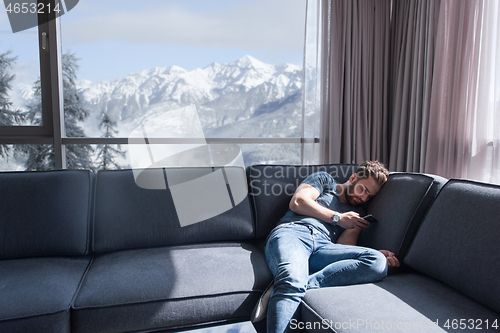 Image of young casual man using a mobile phone at home