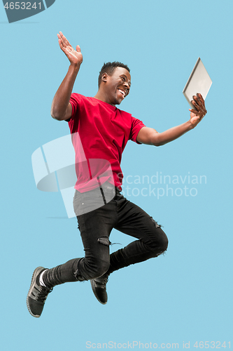 Image of Image of happy excited young african man jumping isolated over yellow background using laptop