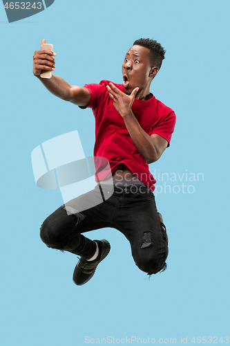 Image of always on mobile. Full length of handsome young man taking phone while jumping