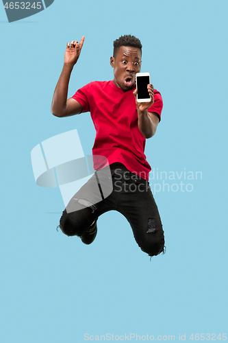 Image of always on mobile. Full length of handsome young man taking phone while jumping