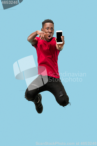 Image of always on mobile. Full length of handsome young man taking phone while jumping