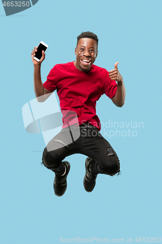 Image of always on mobile. Full length of handsome young man taking phone while jumping