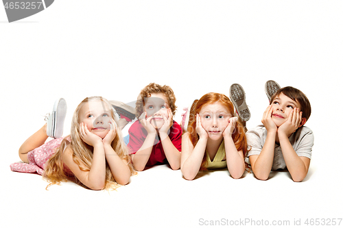 Image of Close-up of happy children lying on floor in studio and looking up, isolated on white background