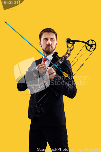 Image of Businessman aiming at target with bow and arrow, isolated on yellow background