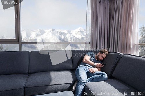 Image of young casual man using a mobile phone at home