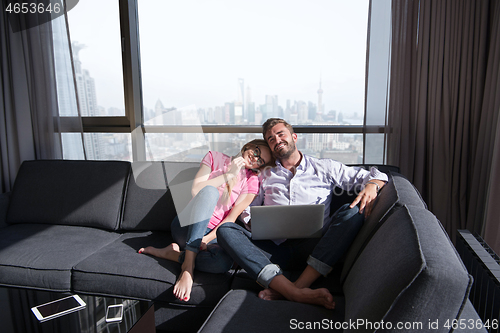 Image of couple relaxing at  home using laptop computers