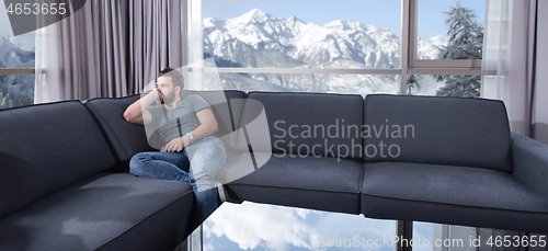 Image of young casual man using a mobile phone at home