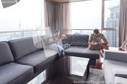 Image of two young men using a mobile phones  at home