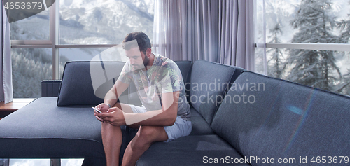 Image of young casual man using a mobile phone at home