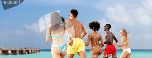 Image of happy friends running on summer beach