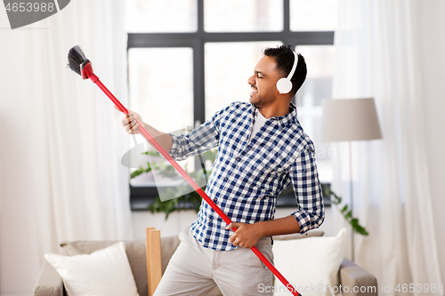 Image of man with broom cleaning and having fun at home