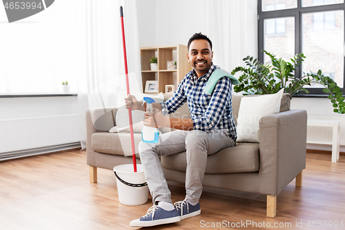 Image of indian man with mop and detergent cleaning at home