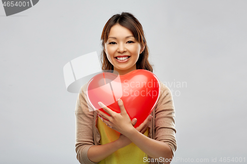 Image of happy asian woman with red heart shaped balloon