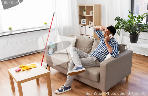 Image of man calling on smartphone after cleaning home