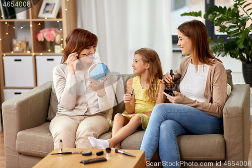 Image of mother, daughter and grandmother doing make up