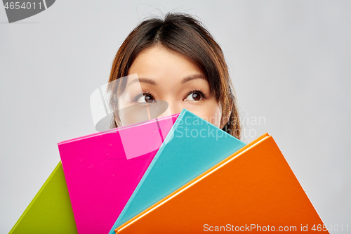 Image of asian woman or student hiding behind notebooks