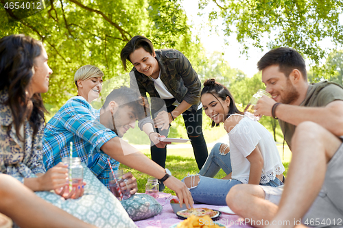 Image of friends with drinks and food at picnic in park