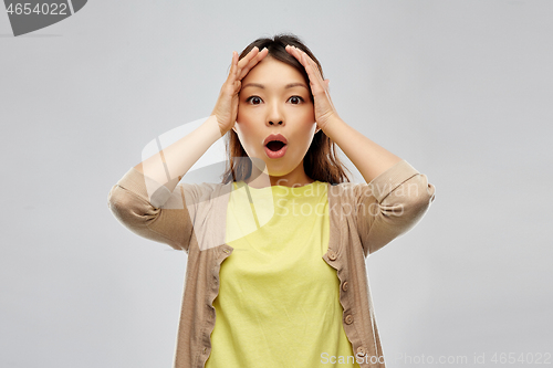 Image of shocked asian woman holding to her head