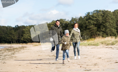 Image of happy family running along autumn beach