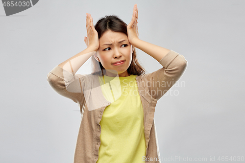 Image of stressed asian woman holding to her head