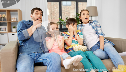 Image of scared family with popcorn watching horror on tv