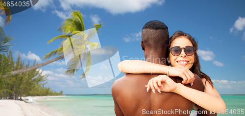 Image of happy mixed race couple hugging on summer beach