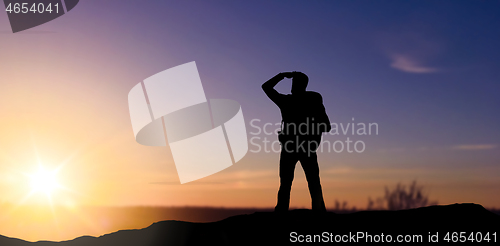 Image of silhouette of tourist looking far away over sunset