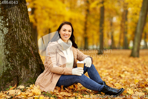 Image of woman drinking takeaway coffee in autumn park