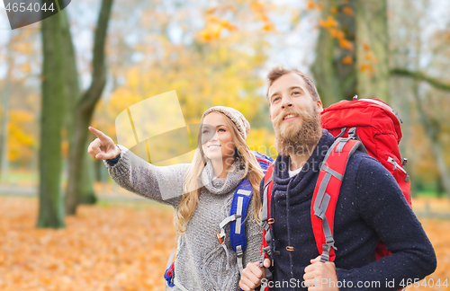 Image of smiling couple with backpacks hiking in autumn
