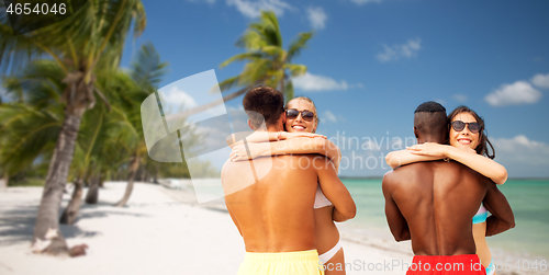 Image of happy friends or couples hugging on summer beach