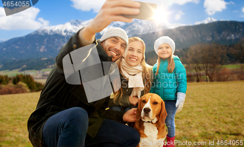 Image of happy family with dog taking selfie in autumn
