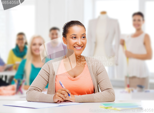 Image of fashion designer with notebook over studio