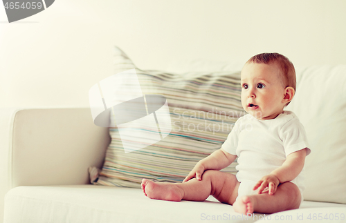 Image of happy baby boy or girl sitting on sofa at home