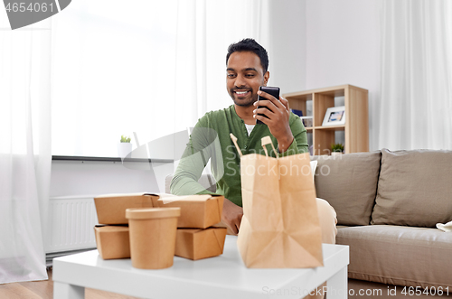 Image of indian man checking takeaway food order at home