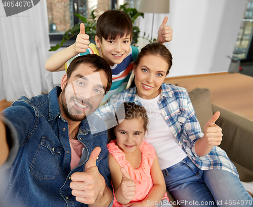 Image of family taking selfie and showing thumbs up at home