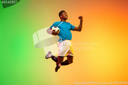 Image of Male soccer, football player training in action isolated on gradient studio background in neon light