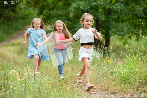 Image of Kids, children running on green meadow, forest. Childhood and summertime