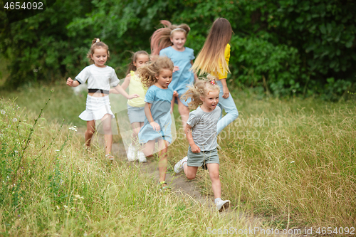 Image of Kids, children running on green meadow, forest. Childhood and summertime