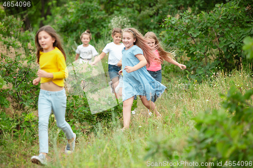 Image of Kids, children running on green meadow, forest. Childhood and summertime