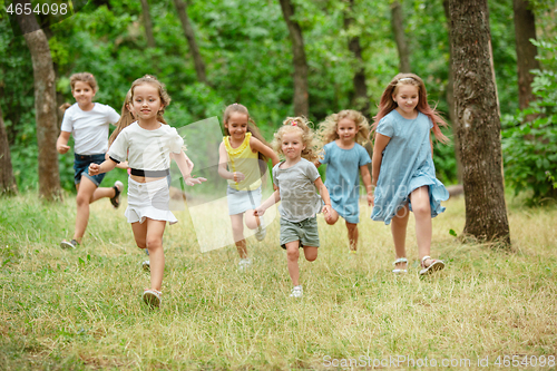 Image of Kids, children running on green meadow, forest. Childhood and summertime