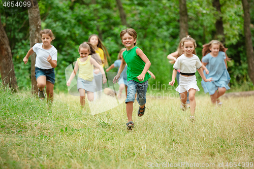 Image of Kids, children running on green meadow, forest. Childhood and summertime