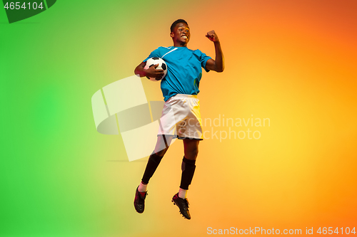 Image of Male soccer, football player training in action isolated on gradient studio background in neon light